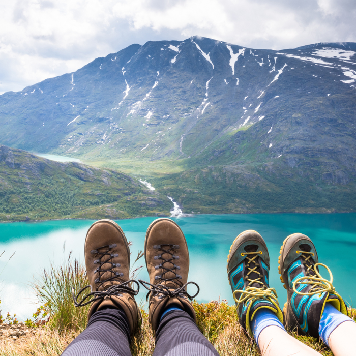 To turgåere tar en pause med utsikt over turkist fjellvann på fjelltur i Norge